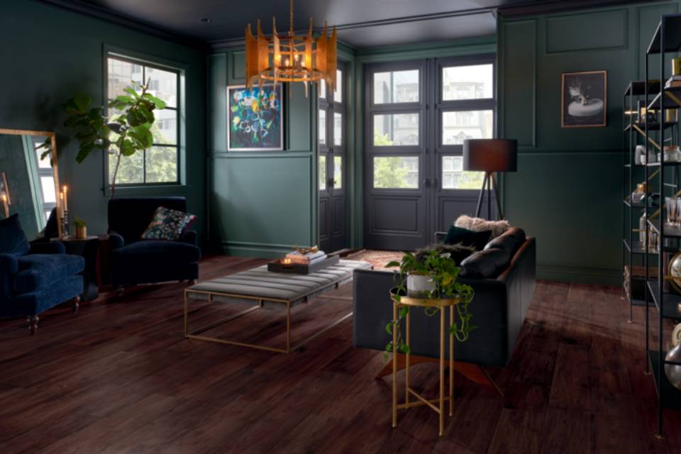 dark wood flooring in living room with green walls and antique furniture.